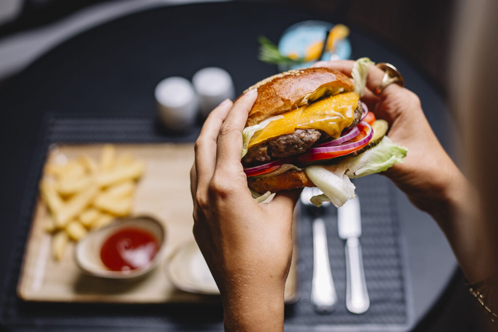 la-donna-tiene-hamburger-di-manzo-con-cipolla-rossa-pomodoro-lattuga-e-formaggio-cheddar-1024x683 Fast food in crescita a Torino, mentre la cucina italiana punta all’Unesco